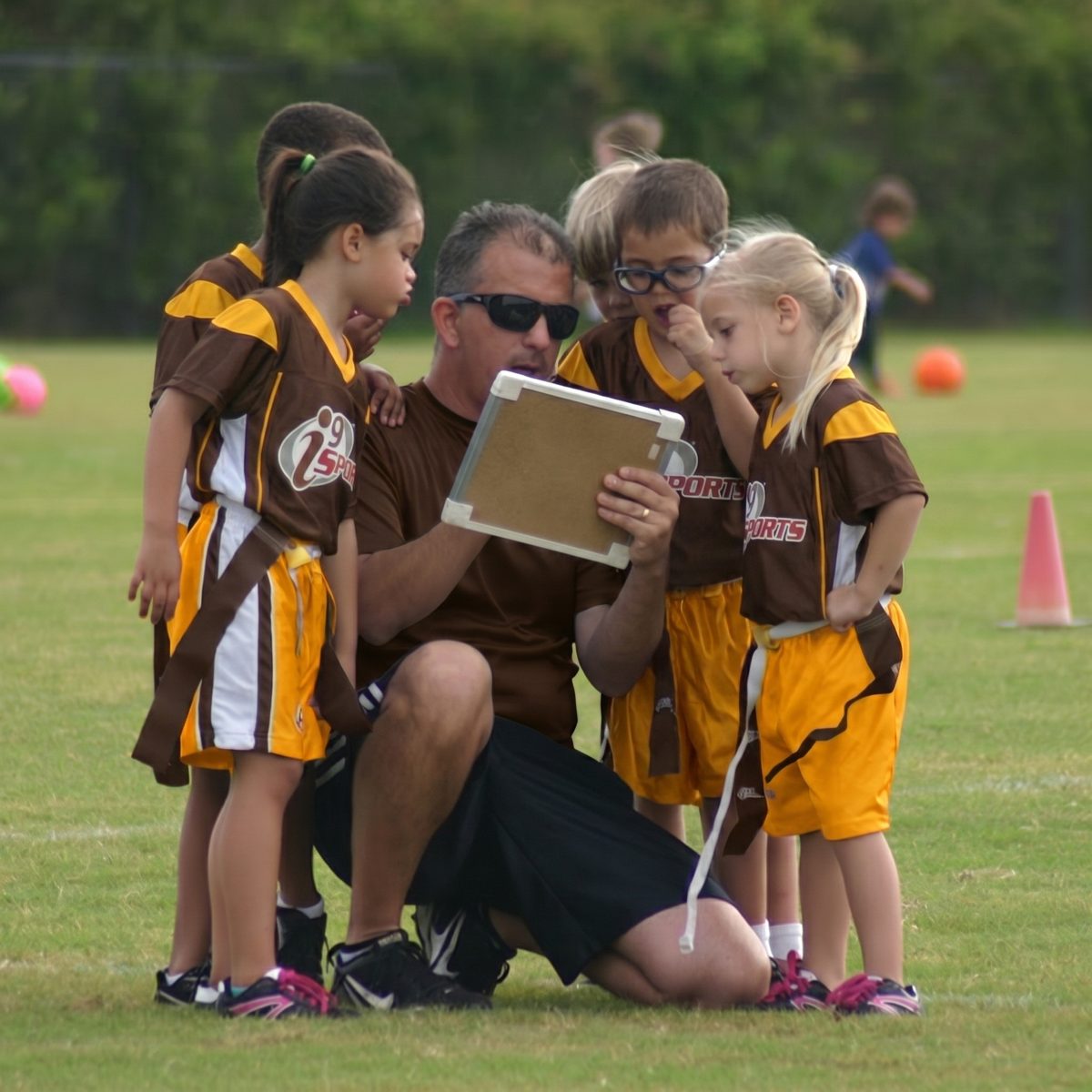 Coach going over a play with young flag players